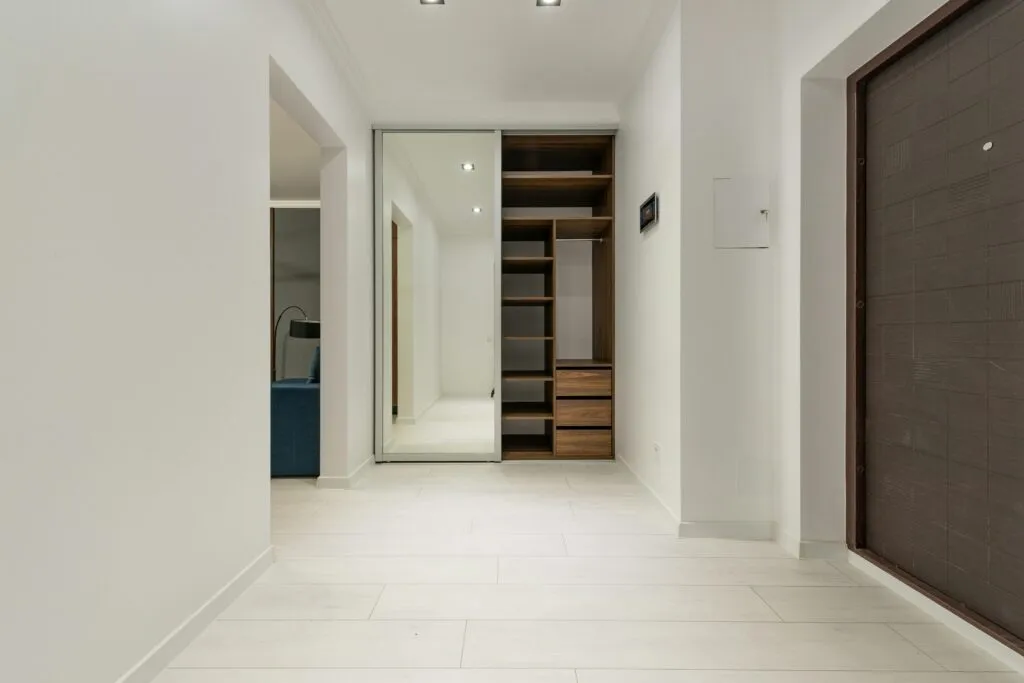 Elegant minimalist corridor with mirrored closet reflecting a modern design.