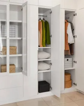 Modern minimalist wardrobe with organized clothes and storage solutions, showcasing a sleek interior design.