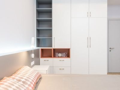 White wardrobe placed near comfortable bed with cushions and bedside table in modern apartment