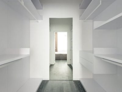 Bright and spacious modern minimalist walk-in closet with open shelving.